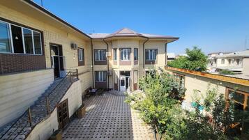 Un immeuble résidentiel de deux étages doté d’une terrasse carrelée, d’un escalier et d’un petit jardin.
