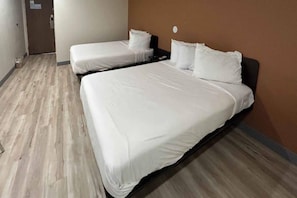 Ein Hotelzimmer mit zwei Einzelbetten, Holzboden und schlichter Wand.