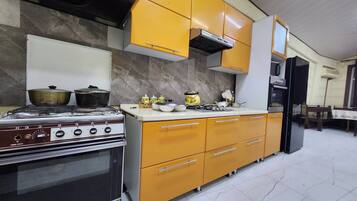 Cozinha com fogão, forno e armários amarelos.