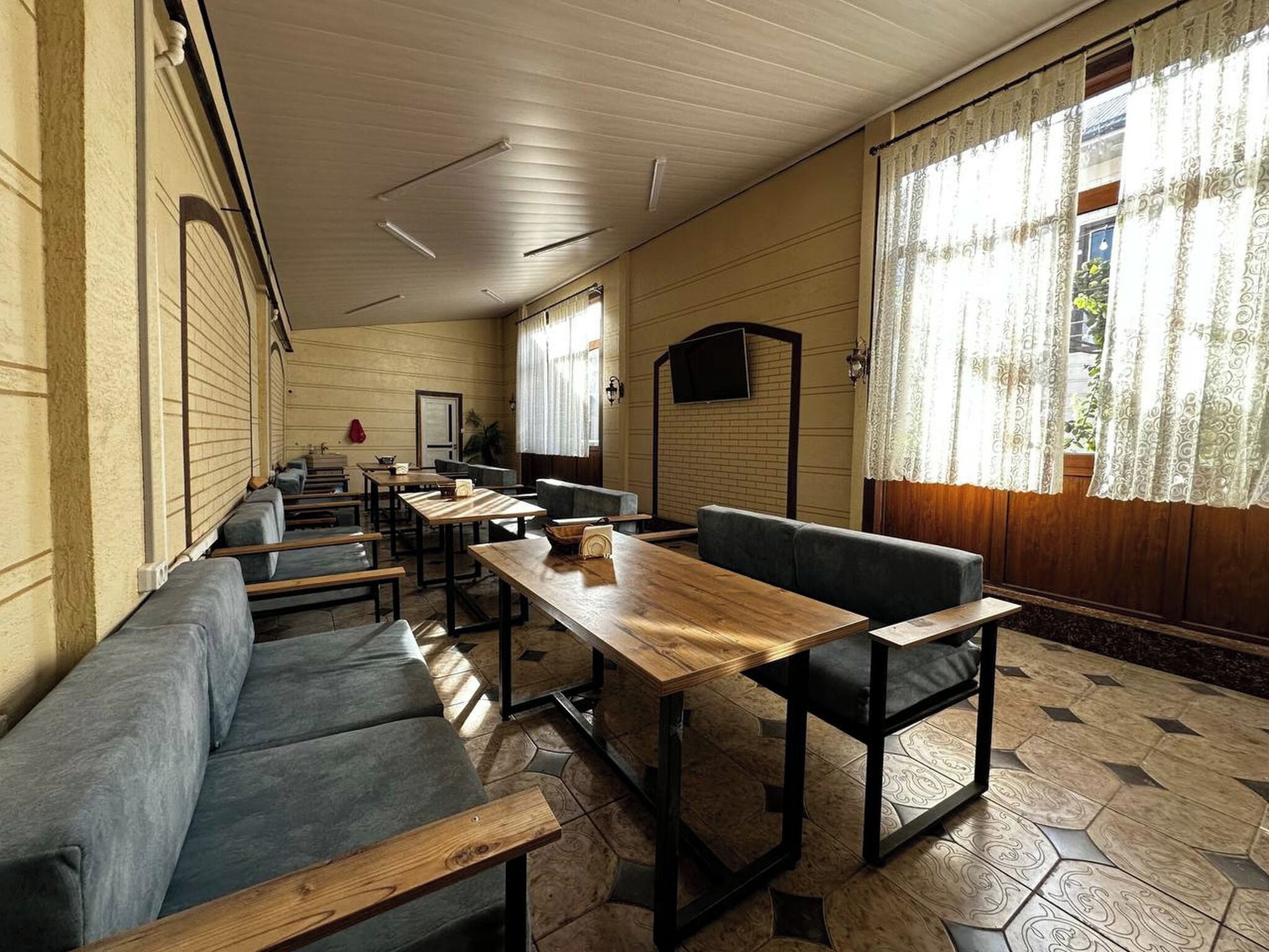 A room with a long table, benches, and a sofa.