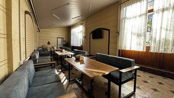 A room with a long table, benches, and a sofa.