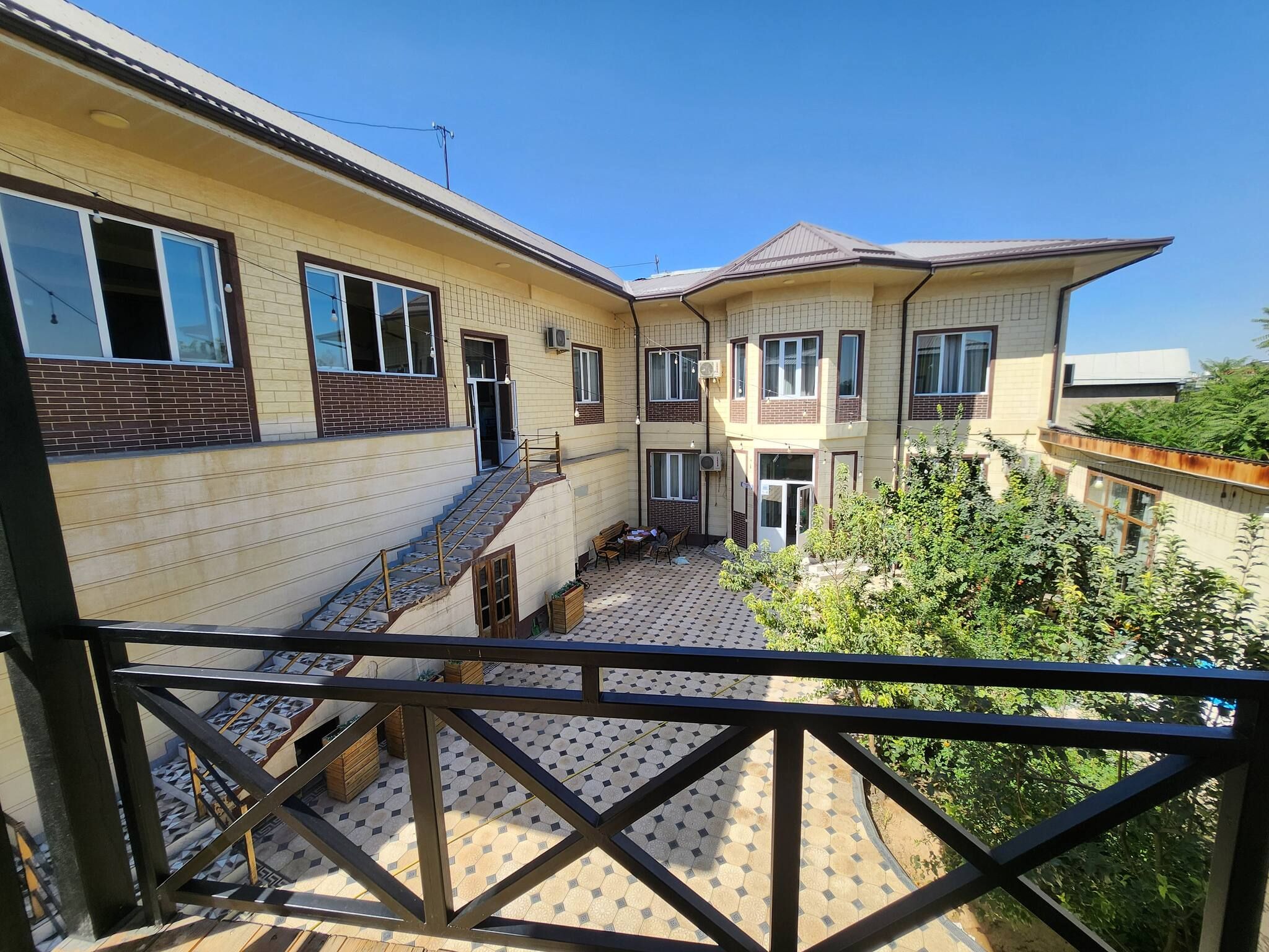 A residential building with multiple windows, a staircase, and a balcony with a tiled floor.