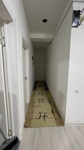 A narrow hallway with a patterned rug, white walls, and a door at the end. - One peaceful room for relaxation (Tashkent)