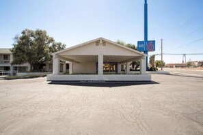 A motel with a covered entrance, a 'No Parking' sign, and a '6' sign indicating the entrance.