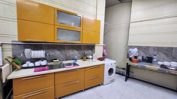 A compact kitchen with a washing machine, a sink, and cabinets.
