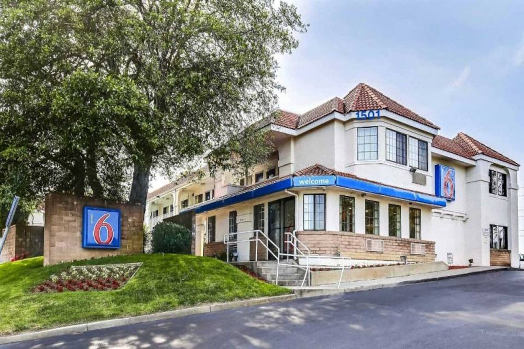 A hotel with a prominent '6' sign, a welcoming entrance, and a well-maintained lawn.