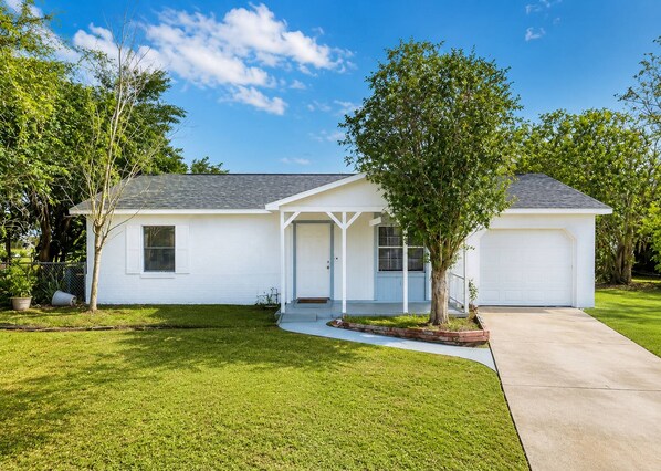 A single-story house with a front porch, a garage, and a well-maintained lawn. - Stay at Our Beautiful Home in Kissimmee (Kissimmee)