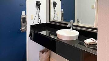 Un bagno con un piano d'appoggio nero, un lavandino bianco e uno specchio.