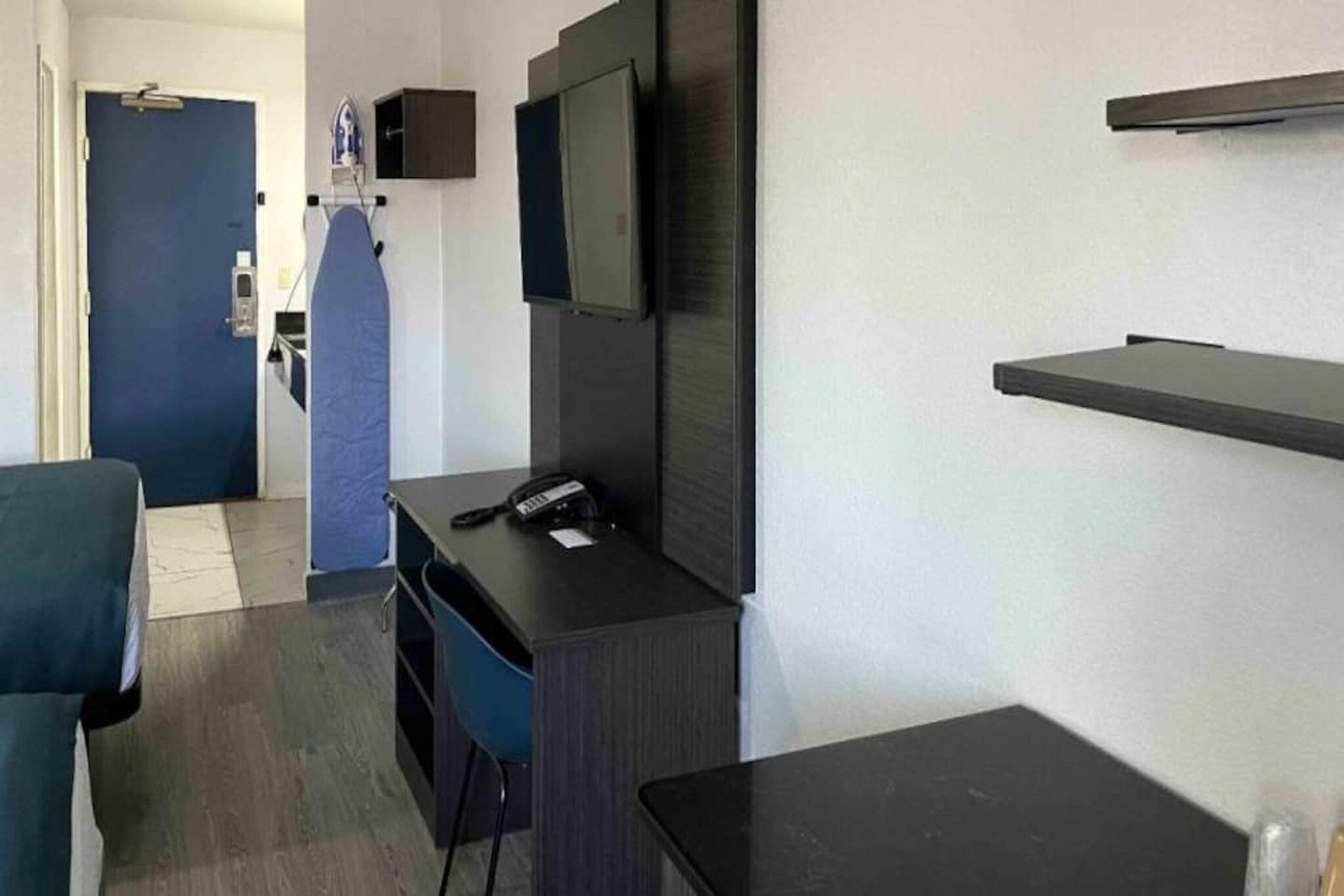 A hotel room with a desk, chair, television, and a small table.