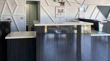 A reception desk with a modern design, a fire alarm, and a door leading to another room.