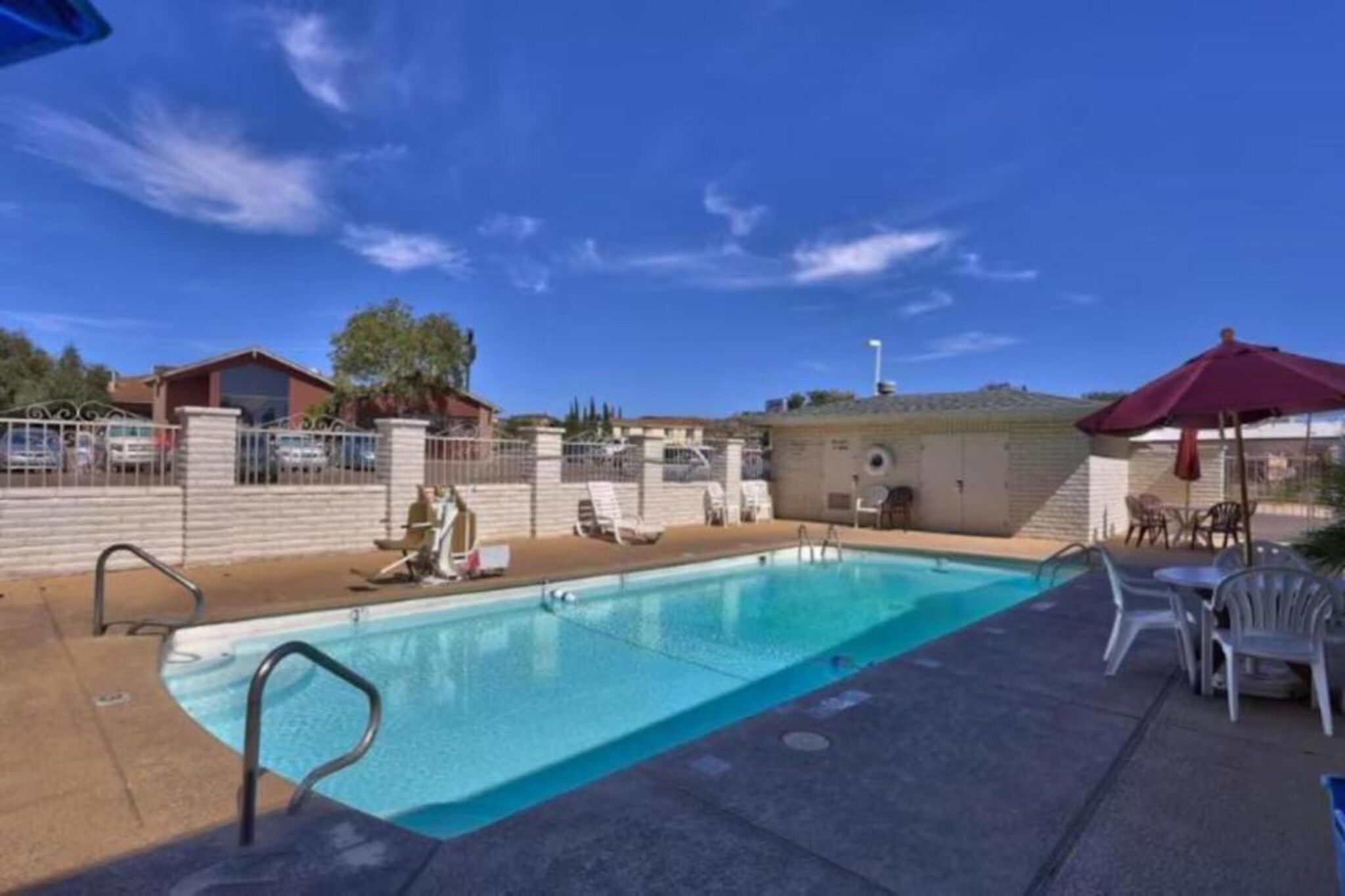 A swimming pool with a surrounding patio area, including lounge chairs and a covered seating area.