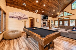 Une pièce chaleureuse avec une table de billard, une cheminée et un canapé.