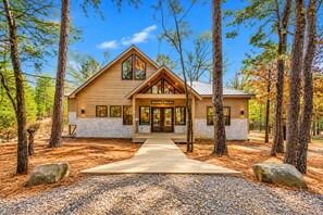 A lodge with a wooden exterior, a stone foundation, and a covered entrance. - Fish Hook Cabin: Hot Tub & Covered Deck (Broken Bow)