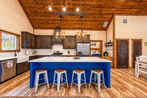 Une cuisine moderne dotée d’un grand îlot central, d’un plafond en bois et de tabourets de bar.