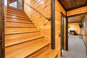 A wooden staircase leading to a room with a foosball table and a window. - Broken Bow Lodge: Hot Tub, Sleeps 18 (Broken Bow)