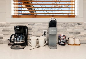 A kitchen with a coffee maker, a Keurig, and coffee pods on the counter. - Modern Cabin w/ Deck & Hot Tub (Broken Bow)