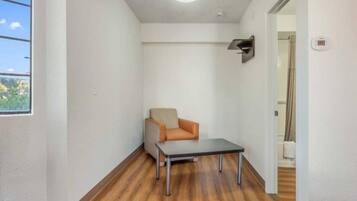 A narrow hallway with a wooden floor, a single chair, and a small table.