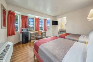 Hotellihuone, jossa on kaksi sänkyä, työpöytä, televisio ja ikkuna, jossa on verhot.