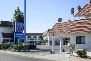 A motel with a clear sign indicating it is number 6. There is a welcoming sign above the entrance, and the building has a traditional architectural style with a tiled roof.