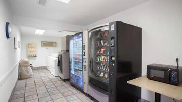 A restroom with two vending machines, a microwave, and a soap dispenser on the wall.