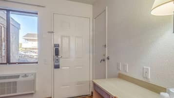 Una habitación con una puerta, una ventana, un aire acondicionado de pared y un mostrador.