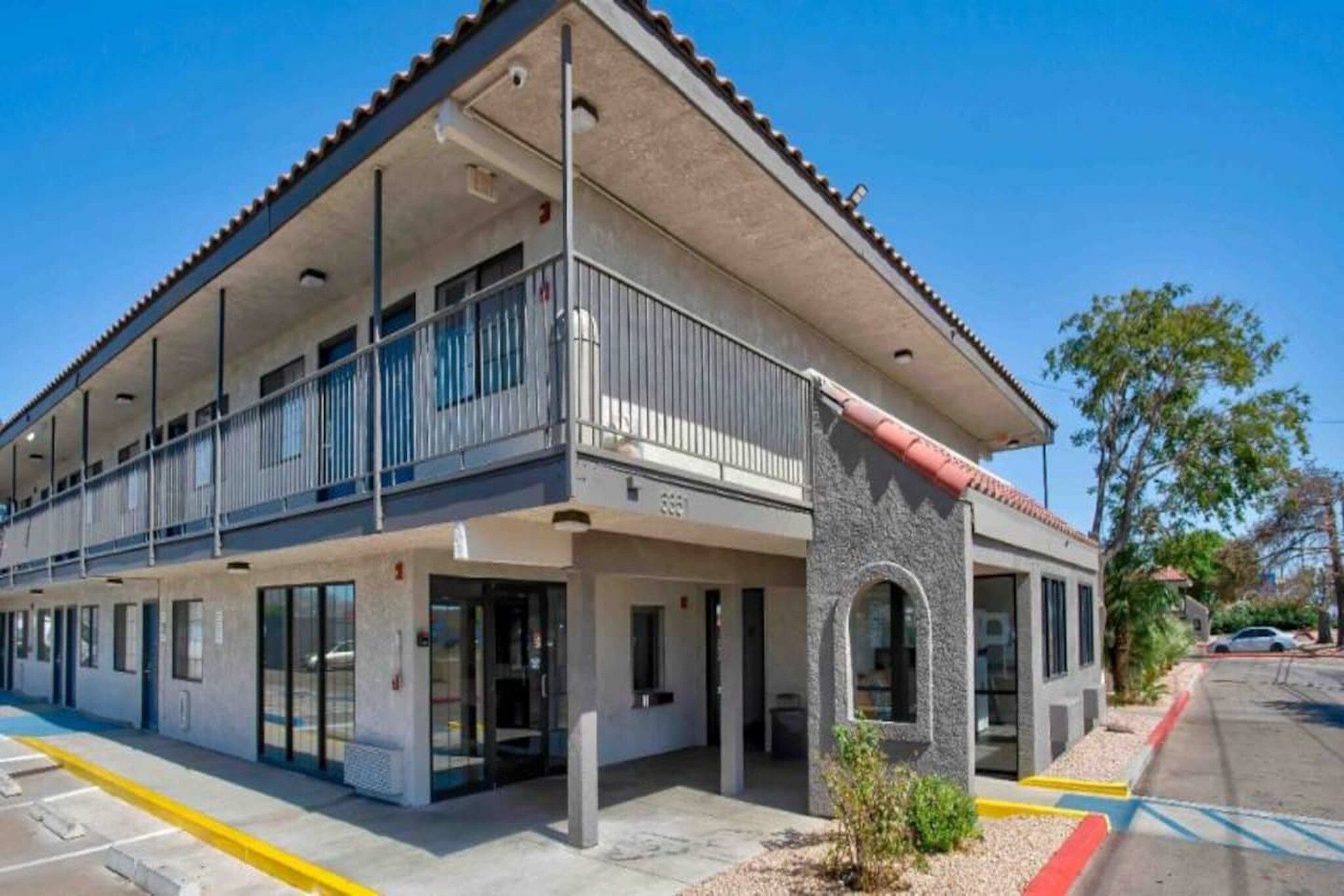A multi-story building with a flat roof, large windows, and a balcony.