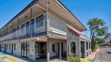 A multi-story building with a flat roof, large windows, and a balcony.