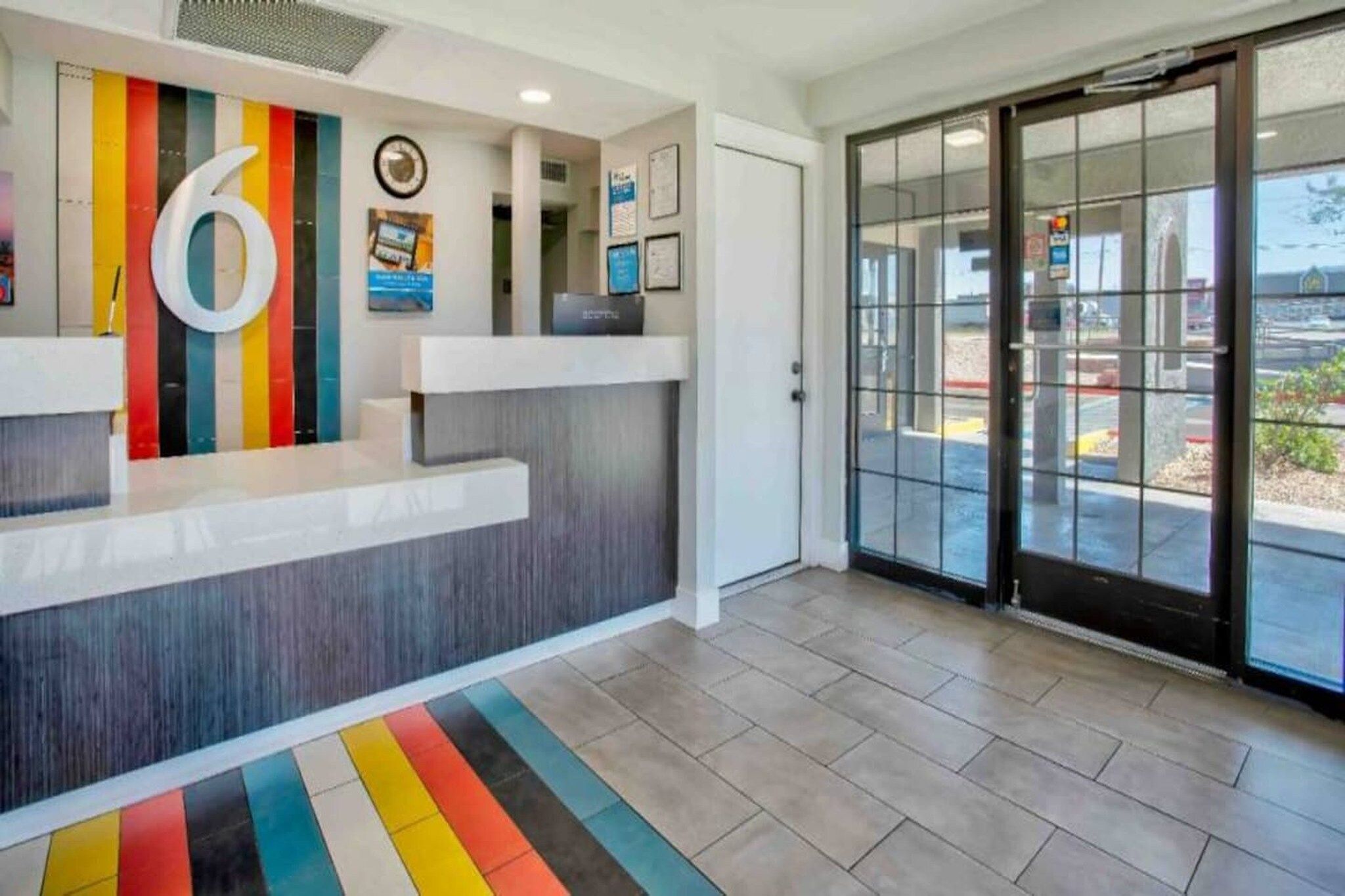 A reception area with a modern design, including a large number '6' sign, a clock, and framed certificates on the wall.