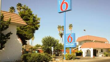 Placa de motel com o número 6 e uma mensagem de boas-vindas, indicando o nome do estabelecimento e seus serviços.