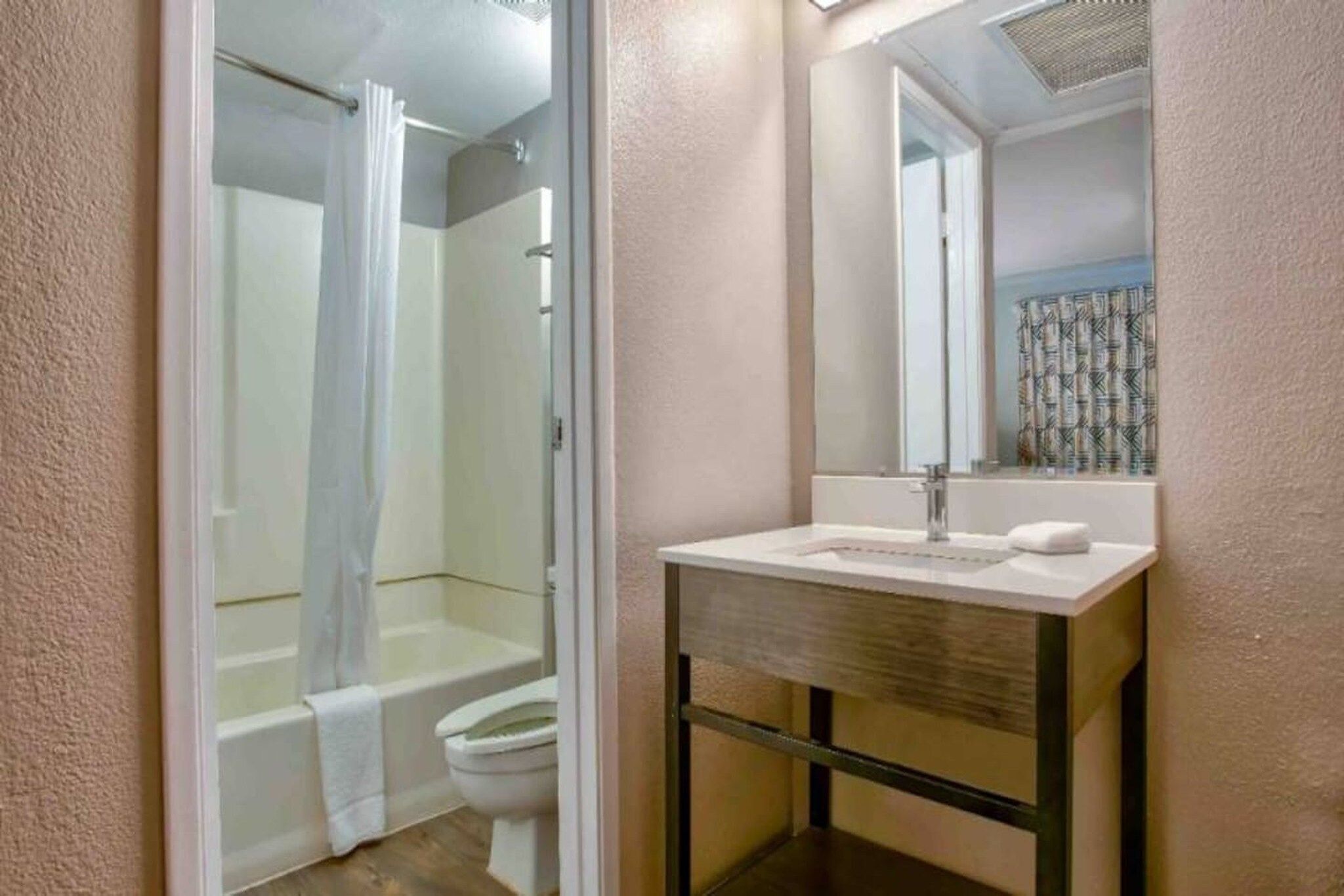 A bathroom with a shower, toilet, and a sink with a mirror.