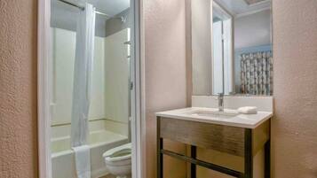 A bathroom with a shower, toilet, and a sink with a mirror.