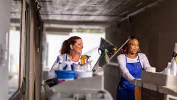 Two individuals in a service area with cleaning supplies and equipment.