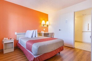 Ein Hotelzimmer mit Bett, Nachttischen, einer Lampe und einer Tür.