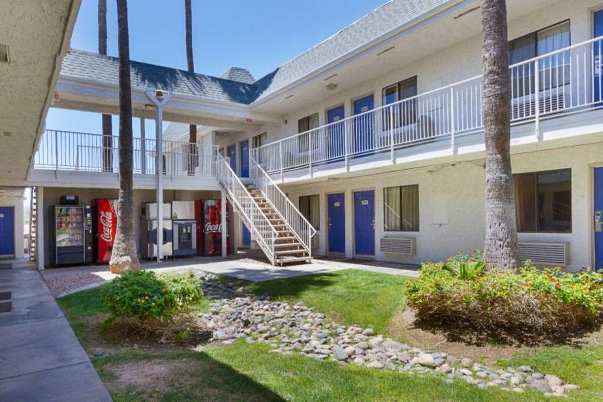 A motel with a central staircase, multiple rooms, and a Coca-Cola vending machine.