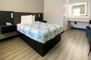 Una habitación de hotel con cama, mesita de noche y espejo.