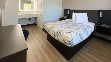 A hotel room with a bed, bedside tables, a desk, and a window.