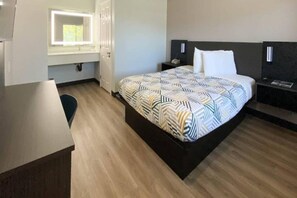A hotel room with a bed, bedside tables, a desk, and a window.