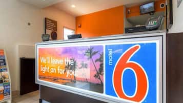 A hotel reception desk with a large sign advertising the hotel name and a message about leaving the light on for guests.