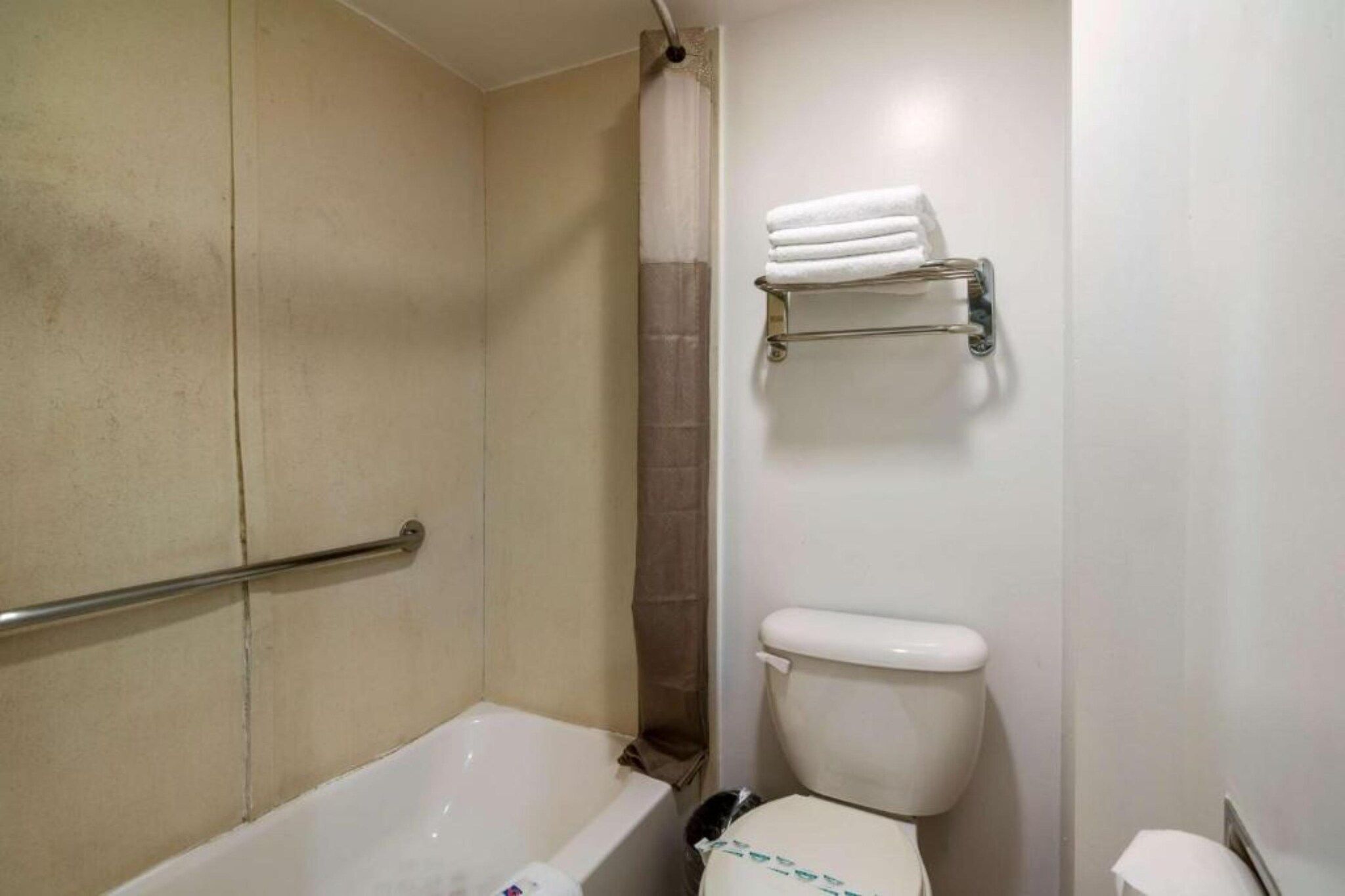 A bathroom with a bathtub, toilet, and shower curtain.