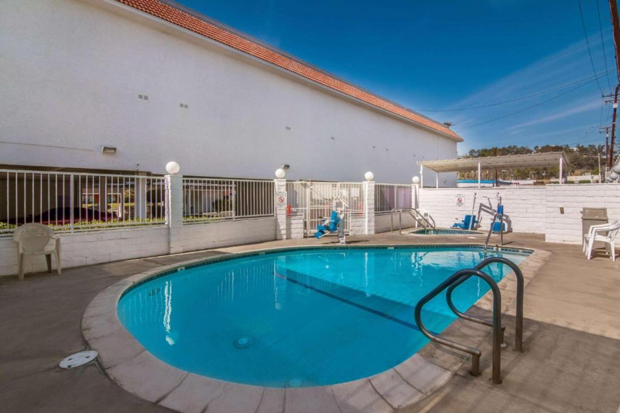 Una piscina con un muro bianco e un tetto piastrellato sullo sfondo.