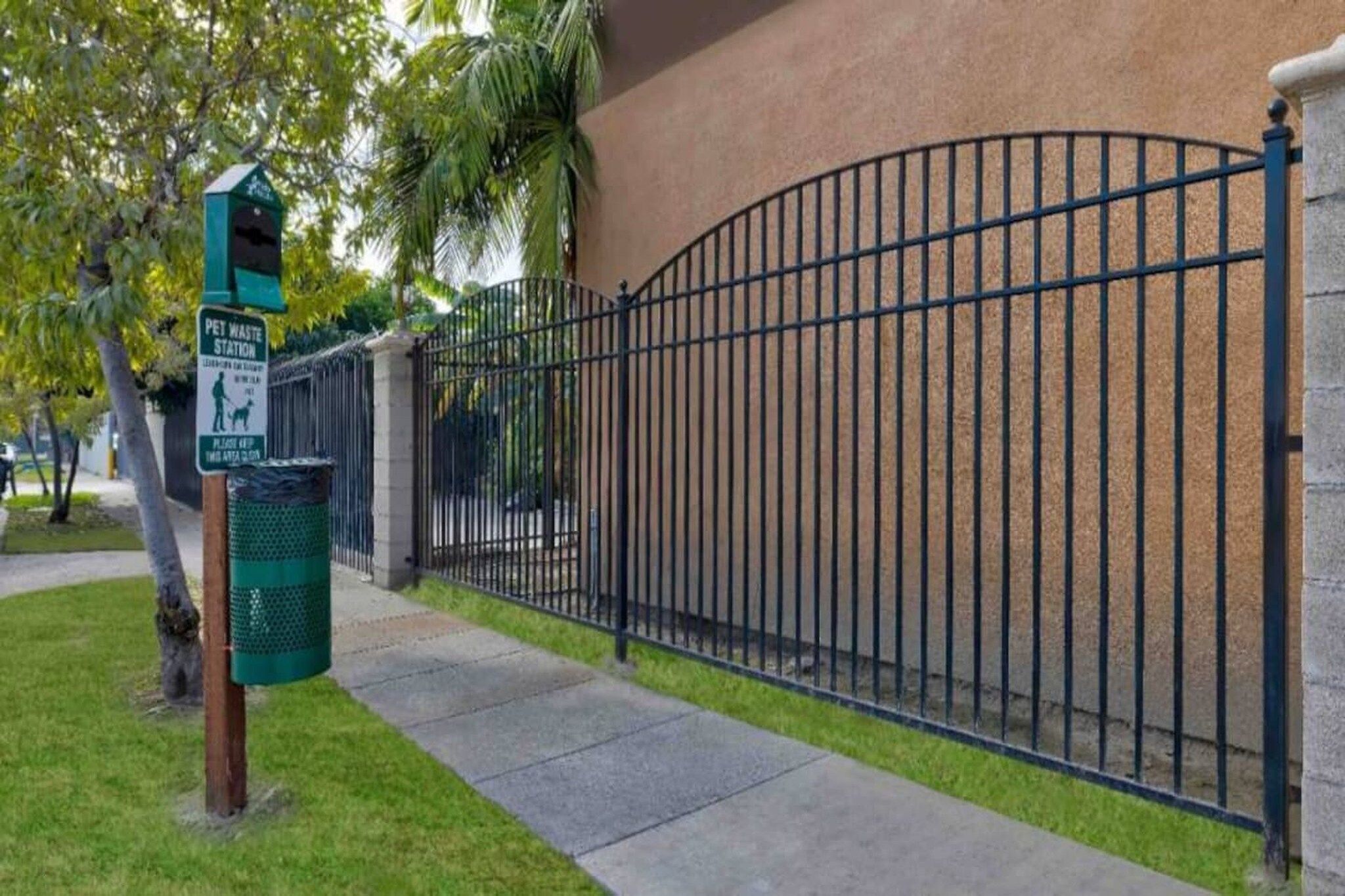 A fenced area with a pet waste station and a trash bin.