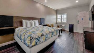 A modern hotel room with a large bed, a desk, a chair, a wardrobe, and a window.