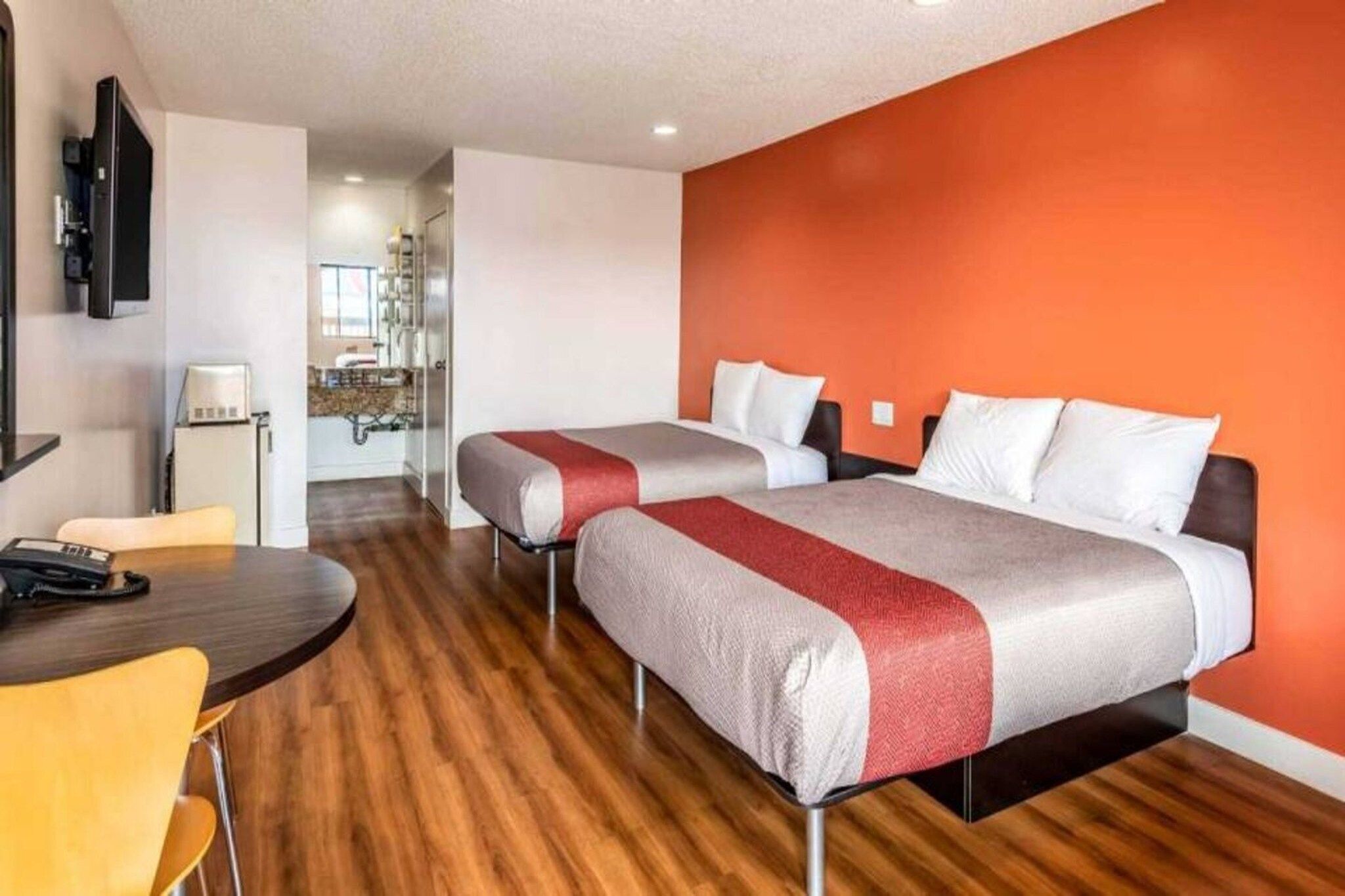 A hotel room with two beds, a desk, and a chair.
