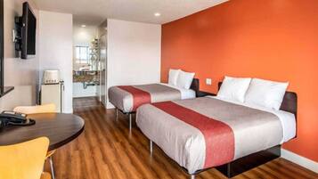 A hotel room with two beds, a desk, and a chair.