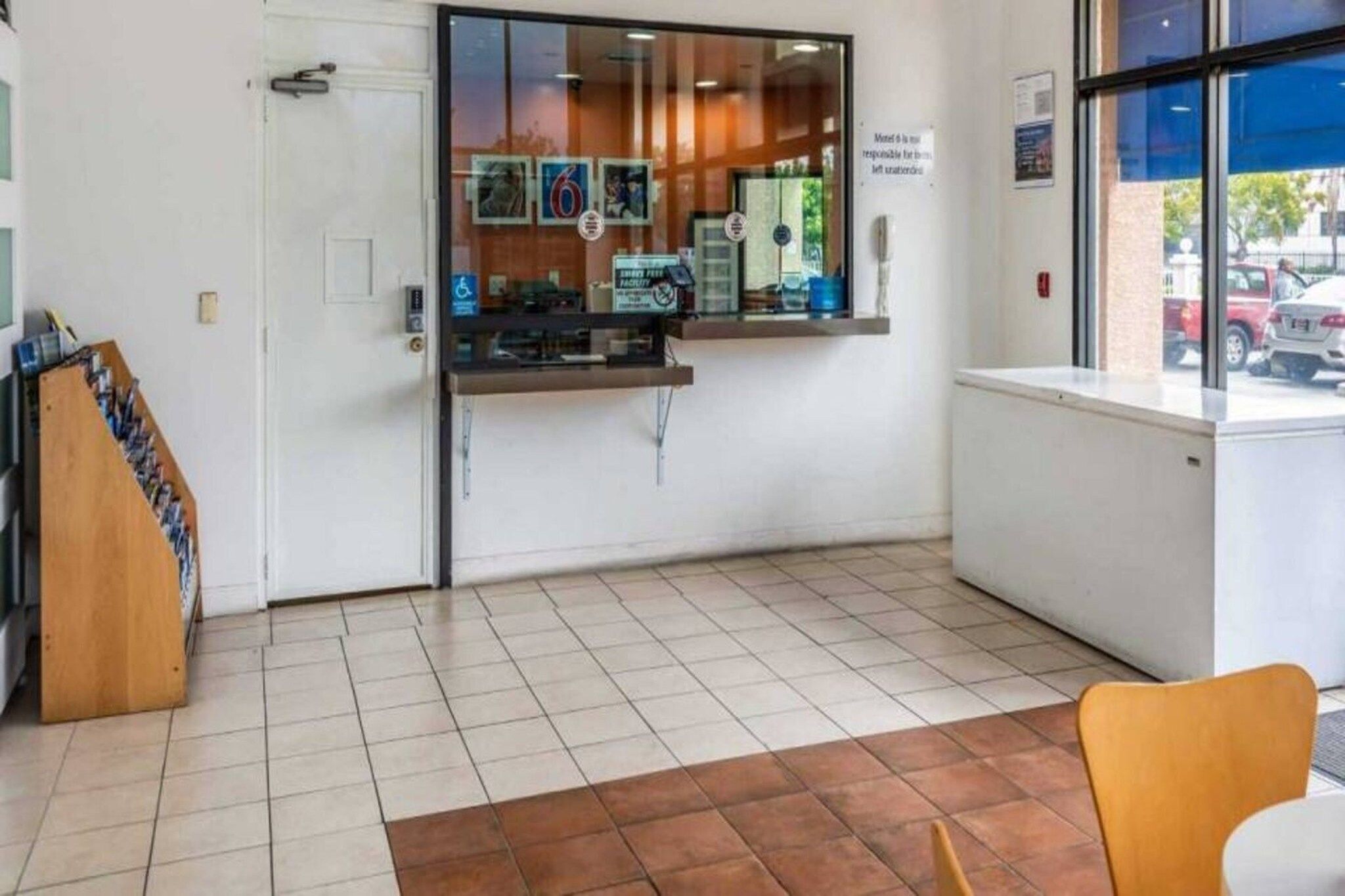 A reception area with a counter, a wheelchair-accessible sign, and a view of parked cars outside.