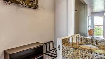 A modern bathroom with a granite countertop sink, a built-in bench, and a towel rack.