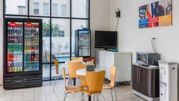 A hotel room with a seating area, a refrigerator with beverages, a television, and a coffee machine.