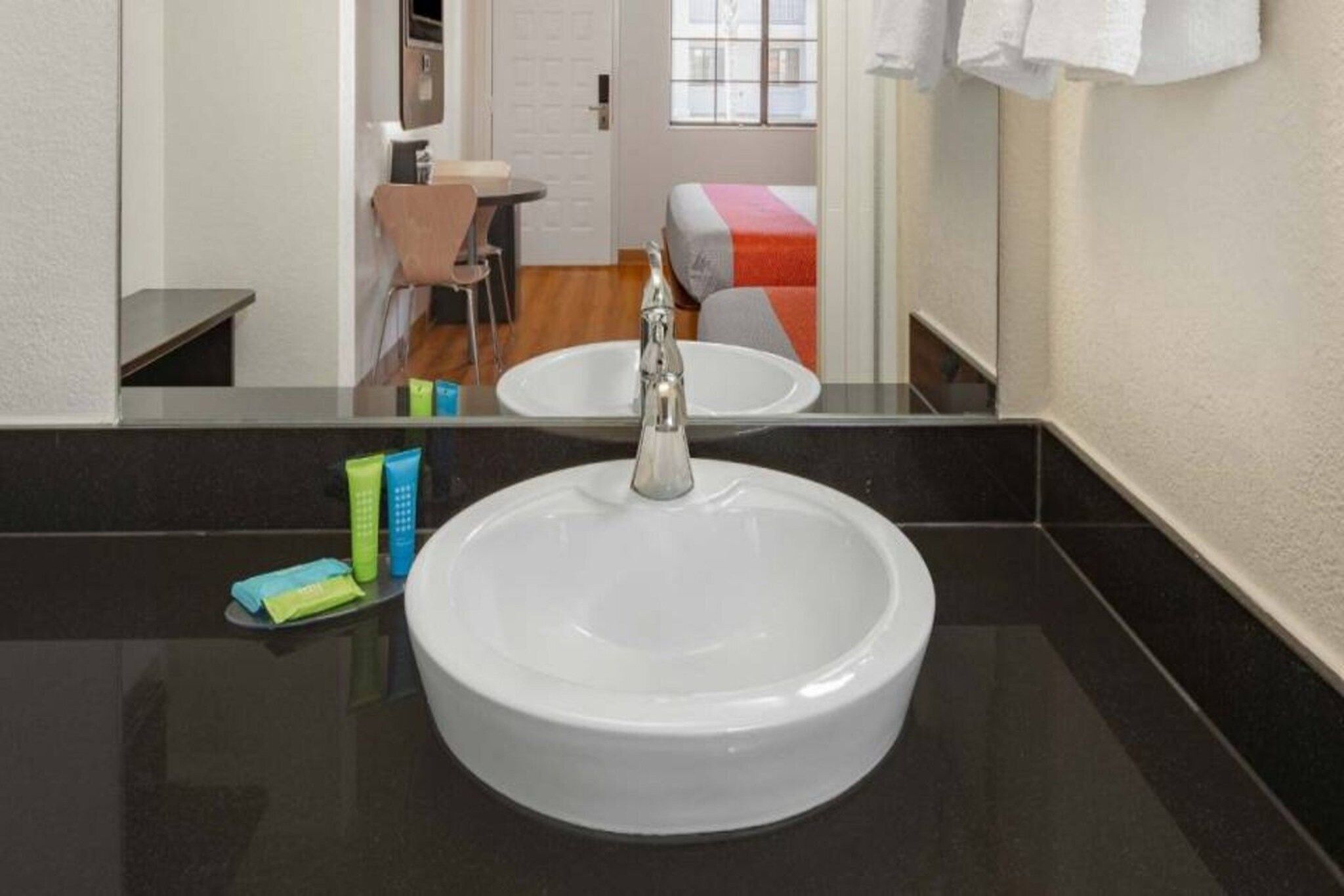 Een badkamer met een witte wastafel, een spiegel en toiletartikelen op het aanrecht.