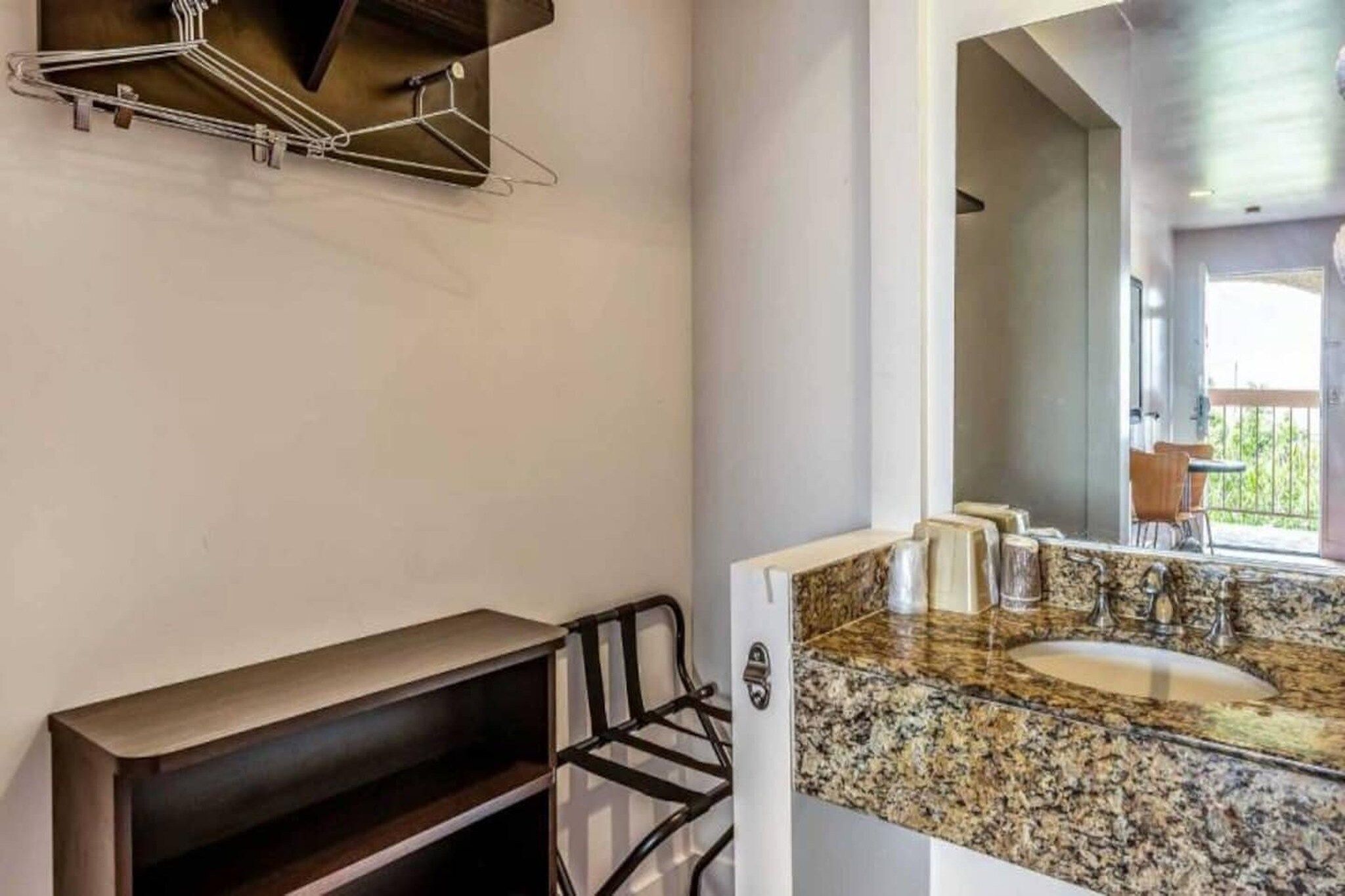 A bathroom with a granite countertop, a sink, and a mirror.