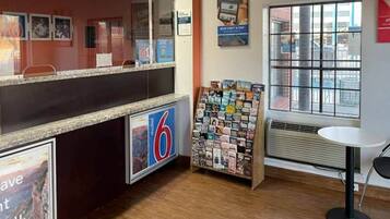 A reception area with a counter, a magazine rack, and a window with a view.